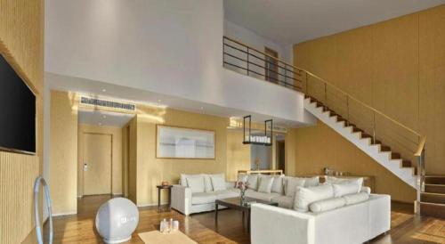 a living room with a white couch and a staircase at Xian Elegant Oriental Hotel in Xi'an