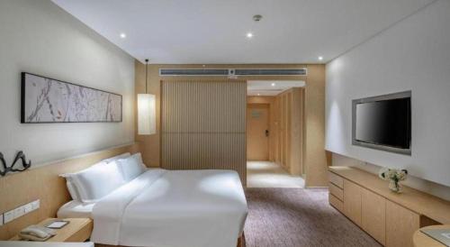 a hotel room with a white bed and a television at Xian Elegant Oriental Hotel in Xi'an