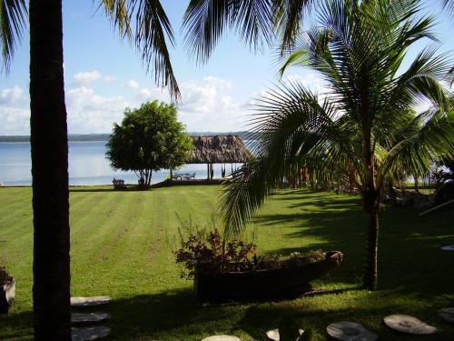 a view of a lawn with palm trees and a house at Hotel Bahia Taitza in Flores