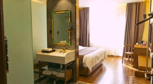 a bathroom with a sink and a bed and a mirror at James Joyce Coffetel Qufu Tourist Center Gulou Street Sankong Scenic Spot in Jining