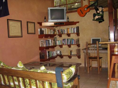 a living room with a tv and shelves of books at Hotel Bahia Taitza in Flores