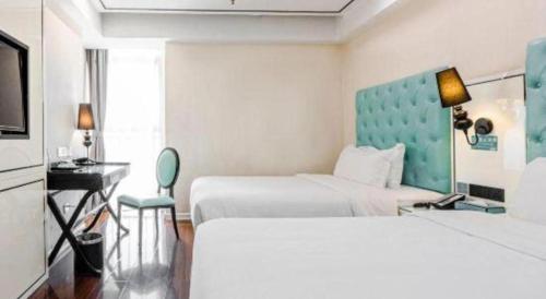 a hotel room with two beds and a desk at Xana Lite Anqing Yuexi Swan Squre Branch in Yuexi