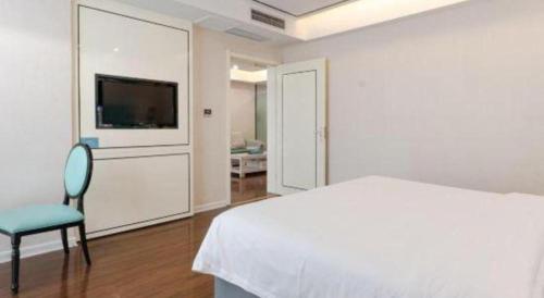 a bedroom with a bed and a chair and a tv at Xana Lite Anqing Yuexi Swan Squre Branch in Yuexi