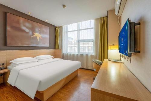 a bedroom with a large white bed and a television at IU Hotels Xinzhou Bus Terminal in Xinzhou