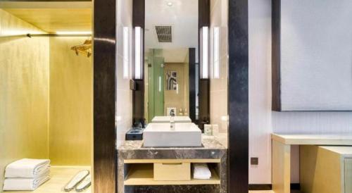 a bathroom with a sink and a mirror at Echarm Hotel Jingjiang Bus Passenger Station Fanggu Street in Jingjiang