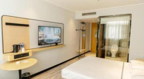 a room with a bed and a tv on a wall at City Comfort Inn Yingcheng Railway Station Shanghe Square in Xiaogan