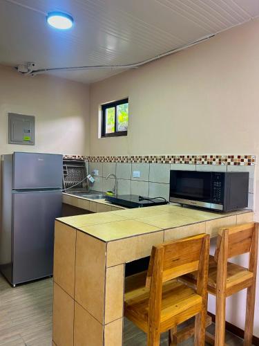 a kitchen with a counter with two chairs and a refrigerator at Good Vibes Apartments in Talamanca