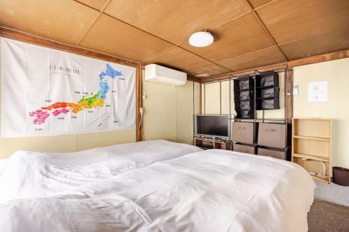 ein Schlafzimmer mit einem großen weißen Bett und einem Fernseher in der Unterkunft 東新小岩5丁目 in Tokio