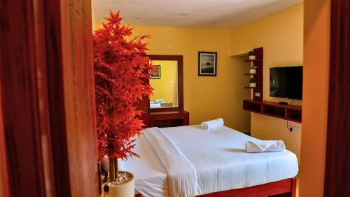 a bedroom with a white bed and a television at Kodai Elliott in Kodaikānāl