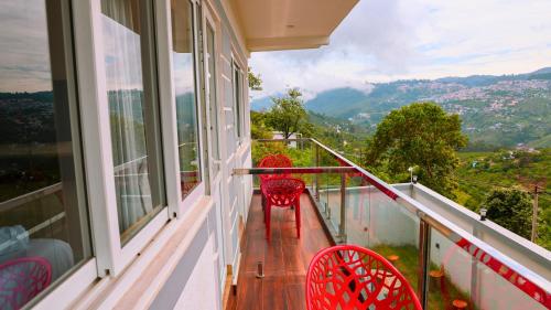 two red chairs sitting on a balcony with a view at Kodai Elliott in Kodaikānāl