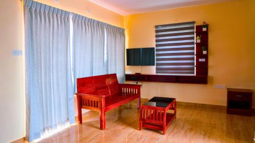 a living room with a red chair and a window at Kodai Elliott in Kodaikānāl