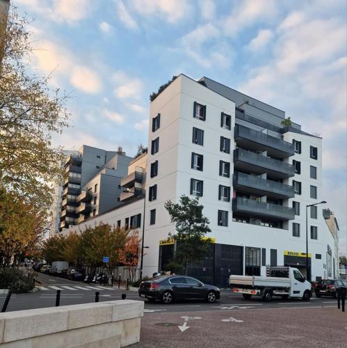 un bâtiment blanc avec un camion garé dans un parking dans l'établissement Appartement aux portes de Paris, à Aubervilliers