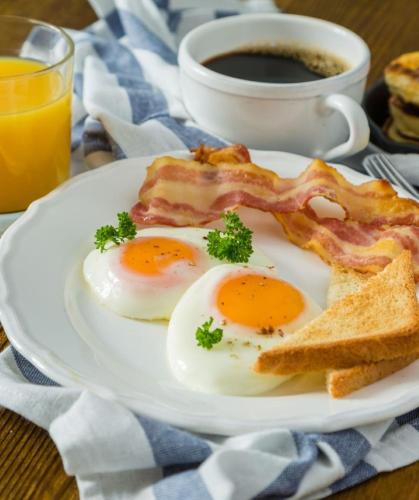 two eggs and bacon on a plate with a cup of coffee at Citadines Sukhumvit 11 Bangkok in Bangkok