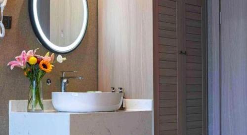 a bathroom with a sink and a vase of flowers at Han Hotel Meisu Xi'an Longshouyuan Shenglong Plaza in Xi'an