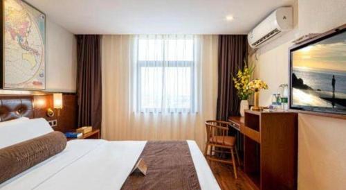 a hotel room with a bed and a desk and a television at James Joyce Coffetel Guilin Railway Station Xiangbi Mountain Liangjiang Sihu Wharf in Guilin