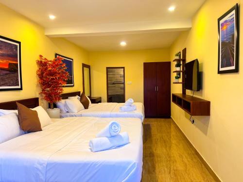two beds in a hotel room with towels on them at Kodai Elliott in Kodaikānāl