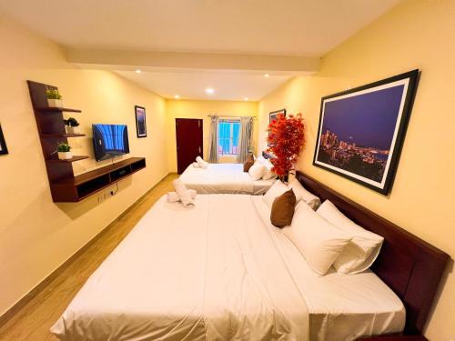 a bedroom with two beds and a flat screen tv at Kodai Elliott in Kodaikānāl