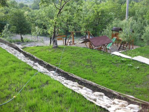 a stone retaining wall in a yard with a playground at Pensiunea Agroturistica Diana in Măgura