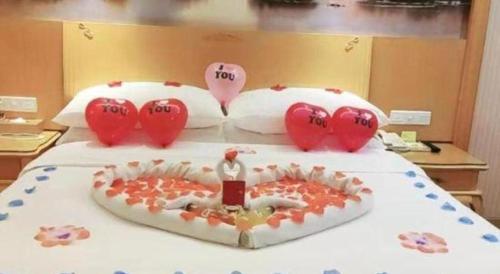 a bed with valentines hearts and a cake on it at Vienna Hotel Guangdong Huiyang Qiuchang Yingbin Road in Huizhou