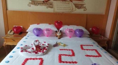 a bed with a cake with hearts and a teddy bear at Vienna Hotel Guangdong Huiyang Qiuchang Yingbin Road in Huizhou