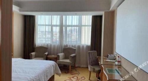 a hotel room with a bed and chairs and a window at Vienna Hotel Guangdong Huiyang Qiuchang Yingbin Road in Huizhou