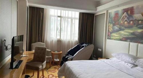 a bedroom with a bed and a desk and a window at Vienna Hotel Guangdong Huiyang Qiuchang Yingbin Road in Huizhou