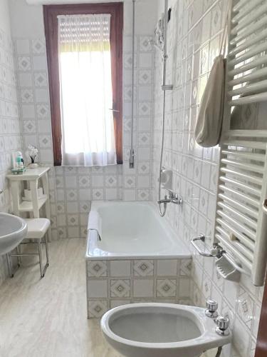a white bathroom with a tub and a sink at IL NIDO by M&G Holiday Home in Soglio