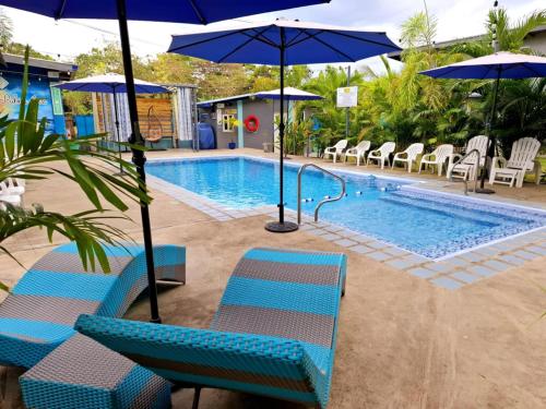 a swimming pool with blue chairs and umbrellas next to a pool at Hidden Palms Inn & Resort Quadruple in San Juan