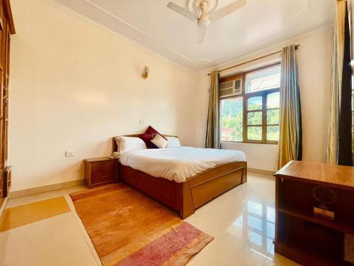 a bedroom with a bed and a window at Ganga Blessing Apartment in Rishīkesh