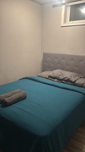 a bed in a bedroom with a blue blanket on it at Flowealth Suites - Private Rooms Near West Edmonton Mall in Edmonton