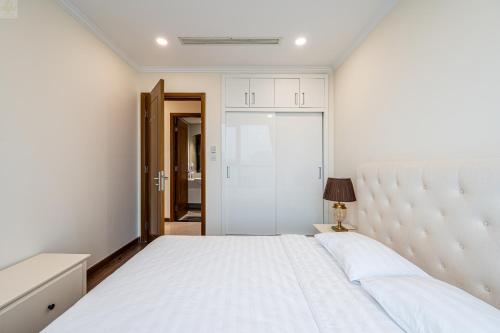 a bedroom with a large white bed with a headboard at Landmark Plus Vinhomes CityView Suite in Ho Chi Minh City