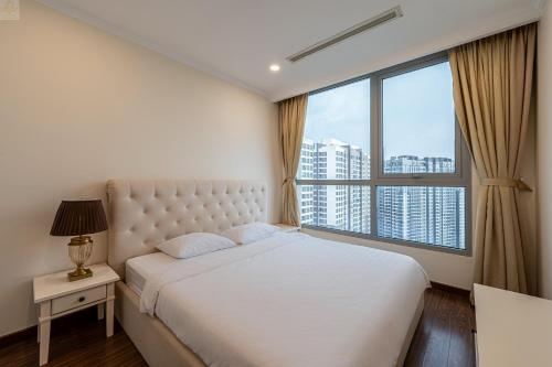 a bedroom with a white bed and a large window at Landmark Plus Vinhomes CityView Suite in Ho Chi Minh City