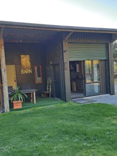 a barn with a bench and a sign on it at Koru Beachfront Holiday Cabins & Hot Tub in Barrytown