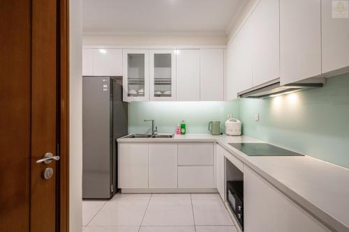 a kitchen with white cabinets and a stainless steel refrigerator at Landmark Plus Vinhomes CityView Suite in Ho Chi Minh City