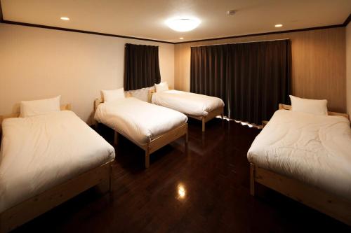 a room with three beds with white sheets at Itoshima inn 海 山 川が目の前でベッド8台 4LDK 一棟貸し in Itoshima