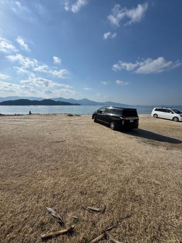 a car parked on a beach next to the water at Itoshima inn 海 山 川が目の前でベッド8台 4LDK 一棟貸し in Itoshima
