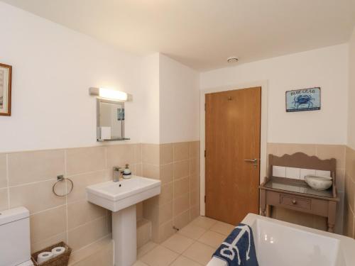 a bathroom with a sink and a toilet and a tub at Sail Away, 17 Union Mill in Whitby