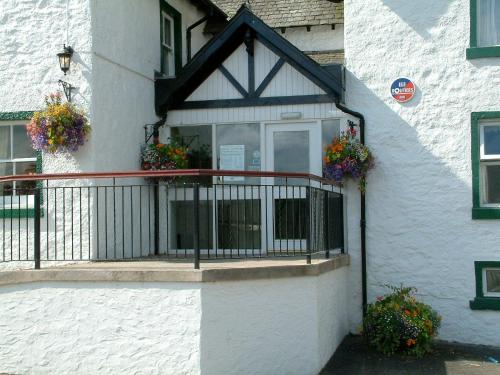 a white building with a balcony with flowers on it at Bridge of Cally Hotel in Blairgowrie