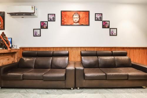 two brown leather seats in a waiting room with pictures on the wall at Hotel O Shri Sai in New Delhi