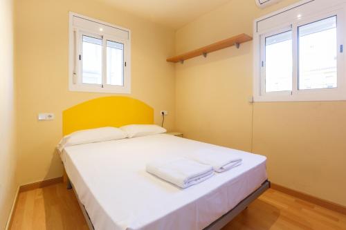 a bedroom with a large white bed with two windows at Apartment Bed&BCN Sant Andreu II in Barcelona