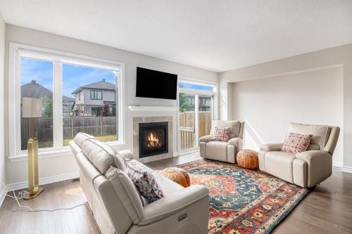 a living room with two chairs and a fireplace at Luxurious Tastefully Furnished 3 bedroom Home in Ottawa in Ottawa