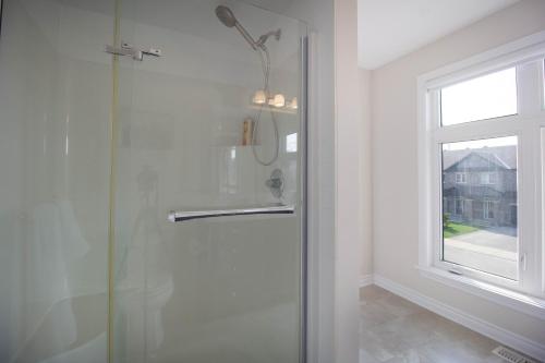 a shower with a glass door and a window at Luxurious Tastefully Furnished 3 bedroom Home in Ottawa in Ottawa