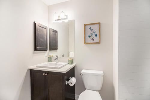 a white bathroom with a toilet and a sink at Luxurious Tastefully Furnished 3 bedroom Home in Ottawa in Ottawa