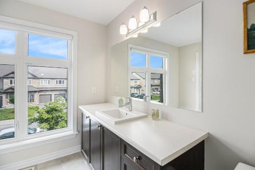 a white bathroom with a sink and a window at Luxurious Tastefully Furnished 3 bedroom Home in Ottawa in Ottawa