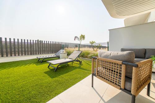 a patio with grass and two chairs and a couch at Rossart Torre del Mar in Torre del Mar