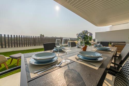 a wooden table with plates and wine glasses on it at Rossart Torre del Mar in Torre del Mar