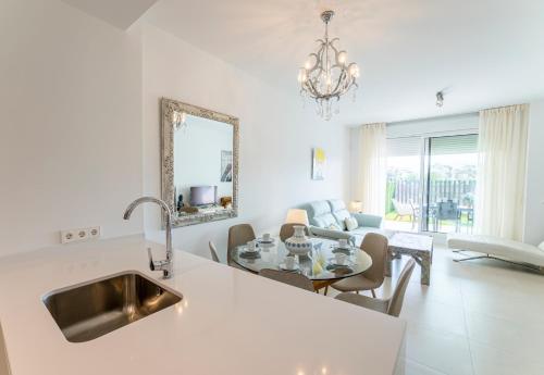 a white kitchen with a sink and a living room at Rossart Torre del Mar in Torre del Mar