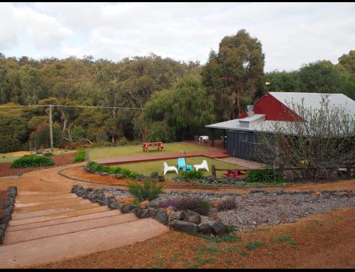 a garden with a red barn and a bench at Wellington Forest Cottages & Bar in Wellington Mills