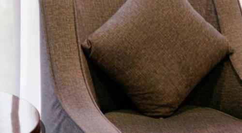 a brown chair with a brown pillow on it at Grand Metropark Hotel Chongqing in Chongqing
