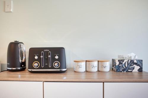a toaster and three coffee cups on a counter at Brand New Guest House in Kenmure Dunedin in Dunedin